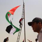 فلسطينيون يرفعون العلم الفلسطيني خلال تظاهرة ضد الاستيطان في قرية النبي صالح
