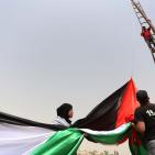 فلسطينيون يرفعون العلم الفلسطيني خلال تظاهرة ضد الاستيطان في قرية النبي صالح