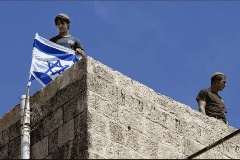 ارشيف- مستوطنون يرفعون العلم الاسرائيلي على منزل فلسطيني