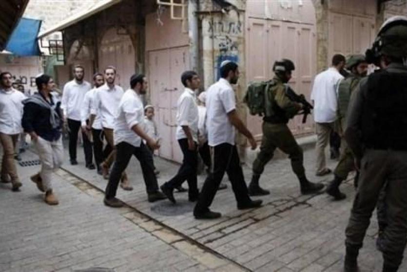 ارشيف- مستوطنون يتجولون بحماية جيش الاحتلال