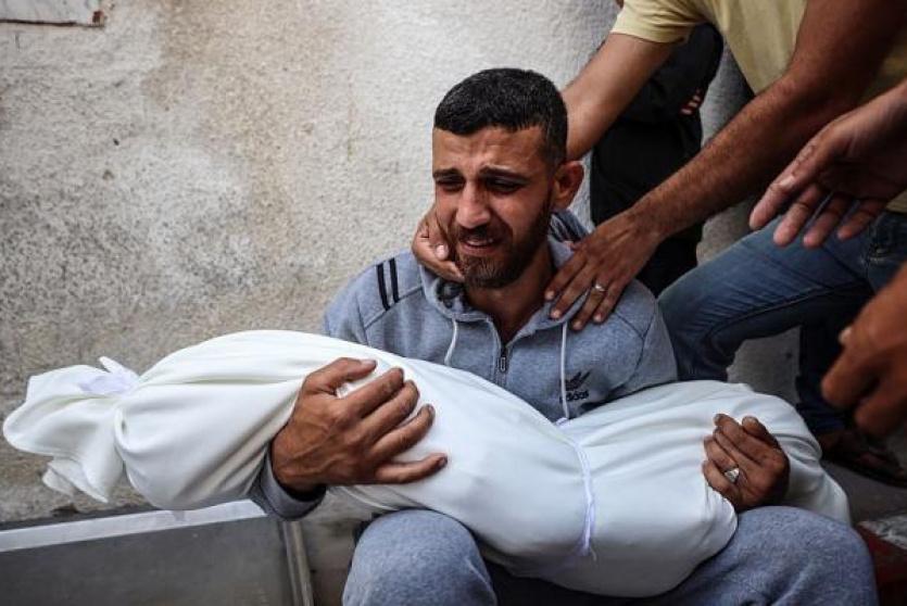 أب يحمل جثمان طفله الشهيد في غزة
